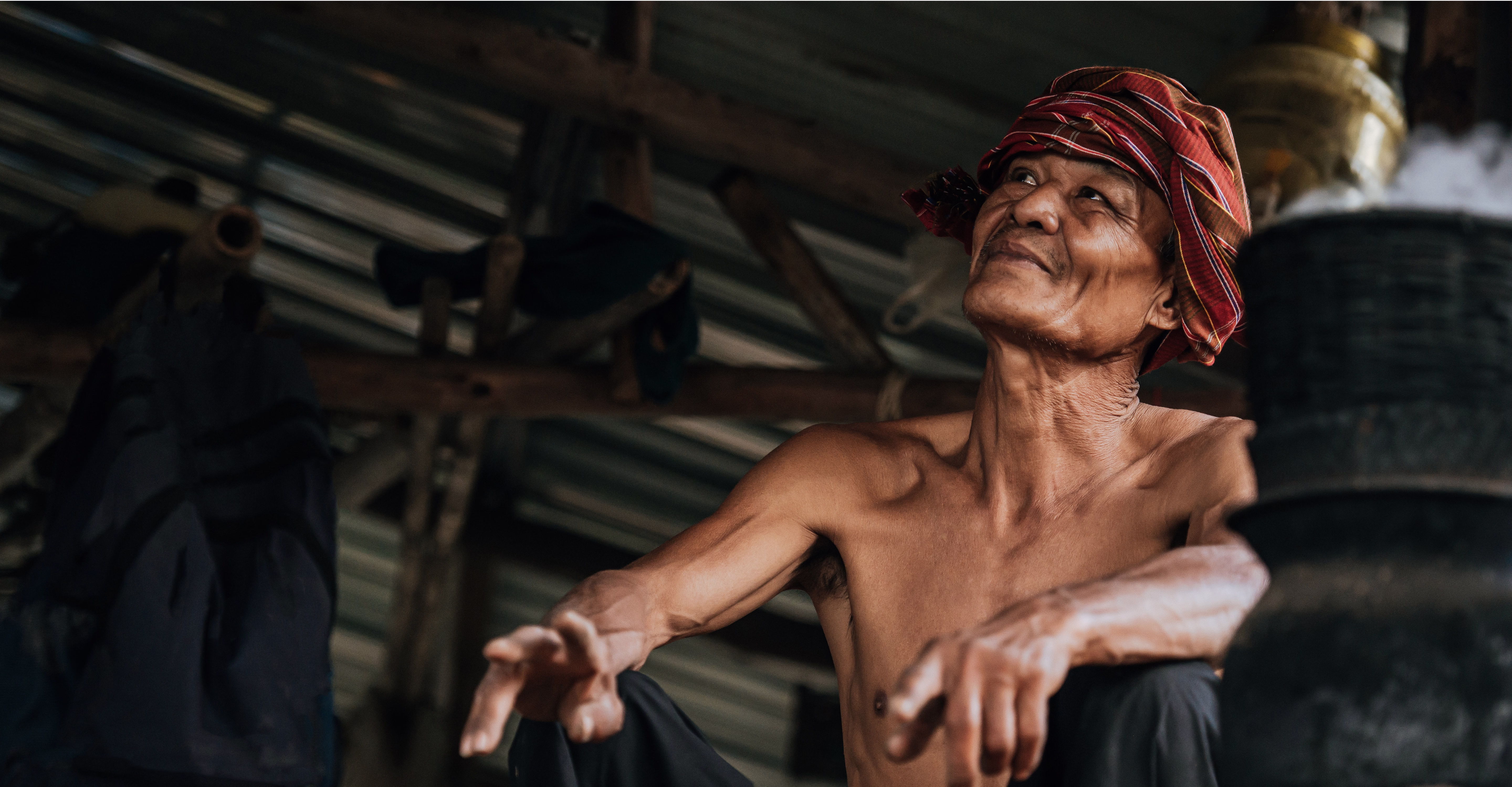 An older community member wearing a red woven headscarf